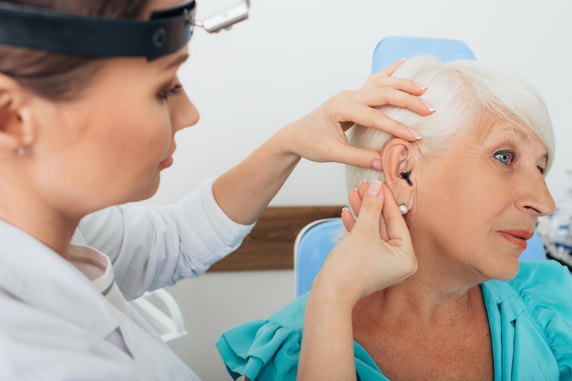 doctor fitting a hearing aid for patient