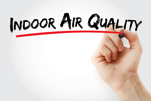 A hand writes "Indoor Air Quality" on the screen of the view with a bold red line underneath the words.
