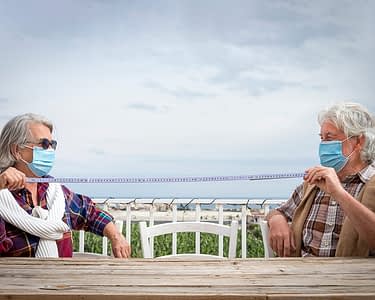 Senior couple wearing masks and demonstrating social distancing.