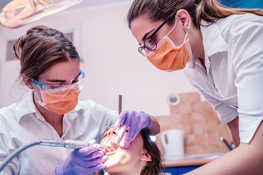 Dental assistant assisting dentist working on patient