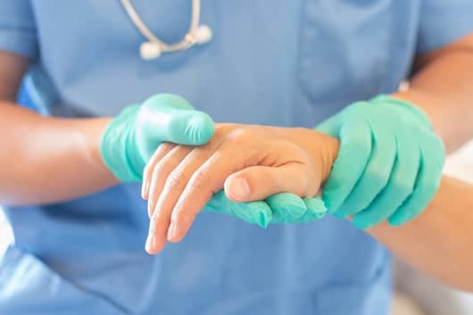 A medical assistant holds a patient’s hand.