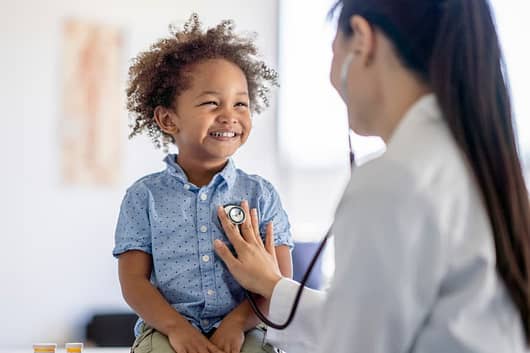 A medical assistant listens to a young boy’s heart.