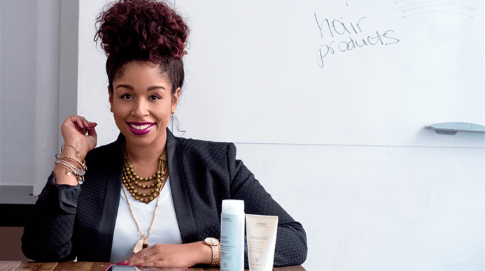 Woman with natural hair sitting with Aveda products