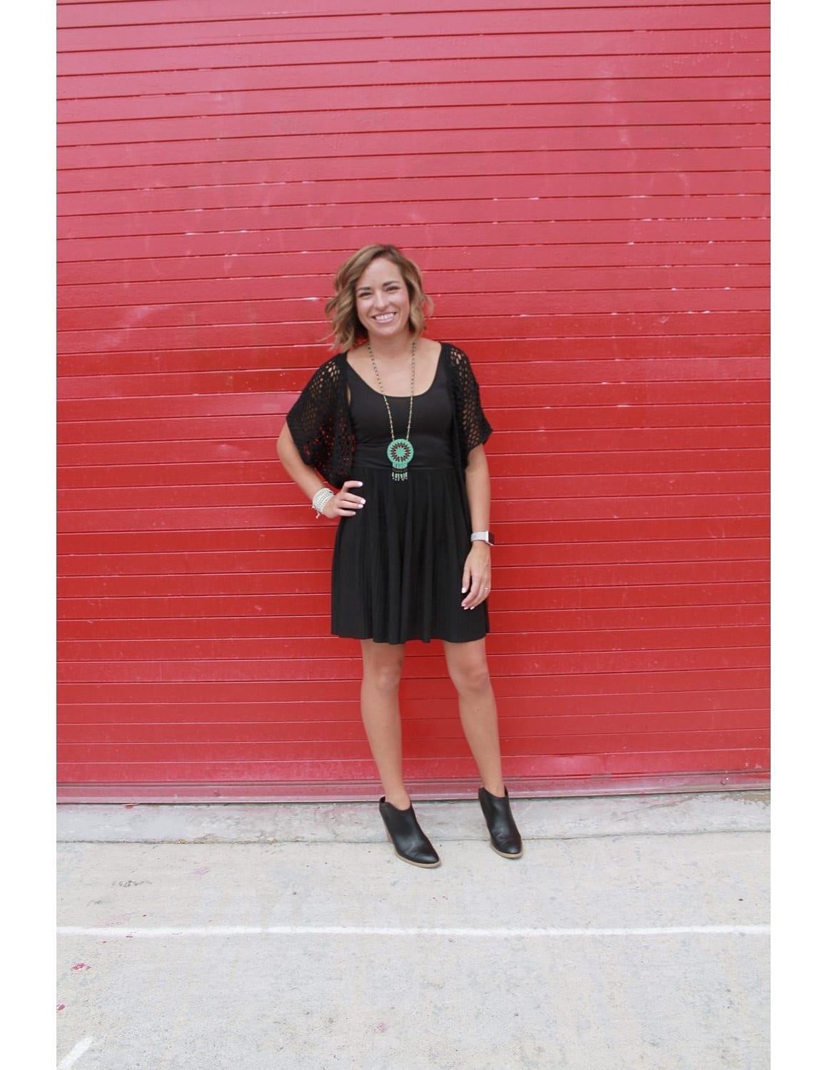 peggy marshall in all black posing in front of a red outdoor wall