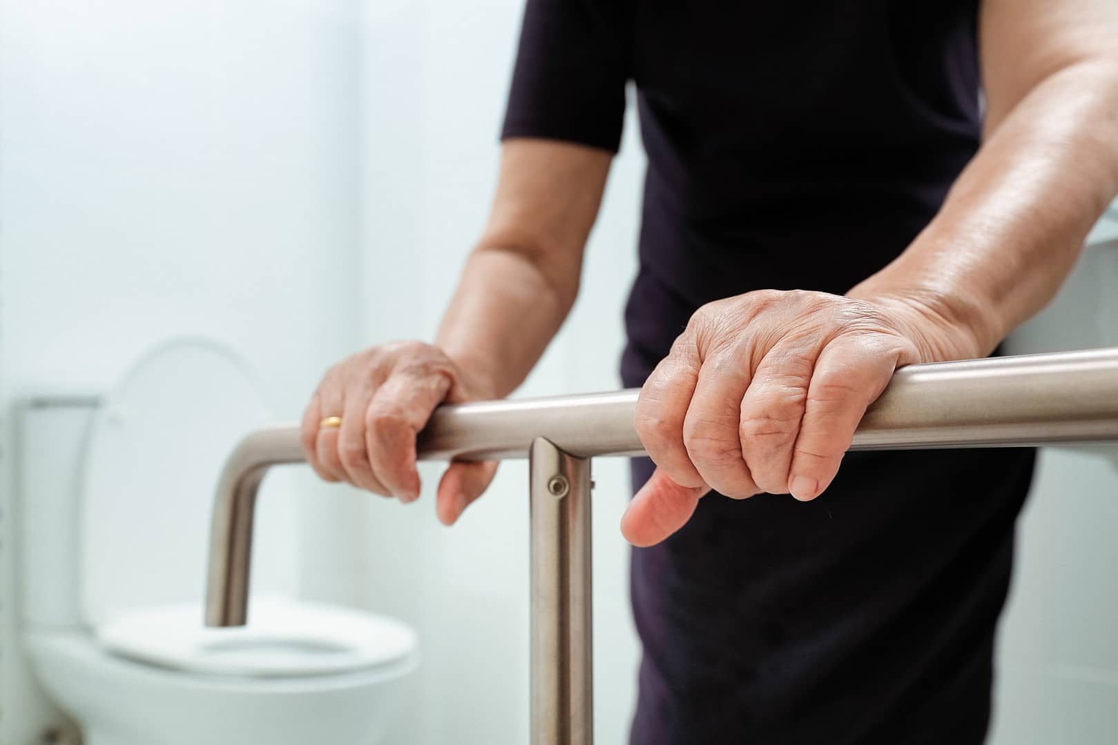 Accessible restroom design is an art, not a science, as depicted in this image of a lady using an ADA-compliant handrail near a toilet.