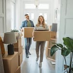 Homeowners carrying boxes to move into larger home with more space