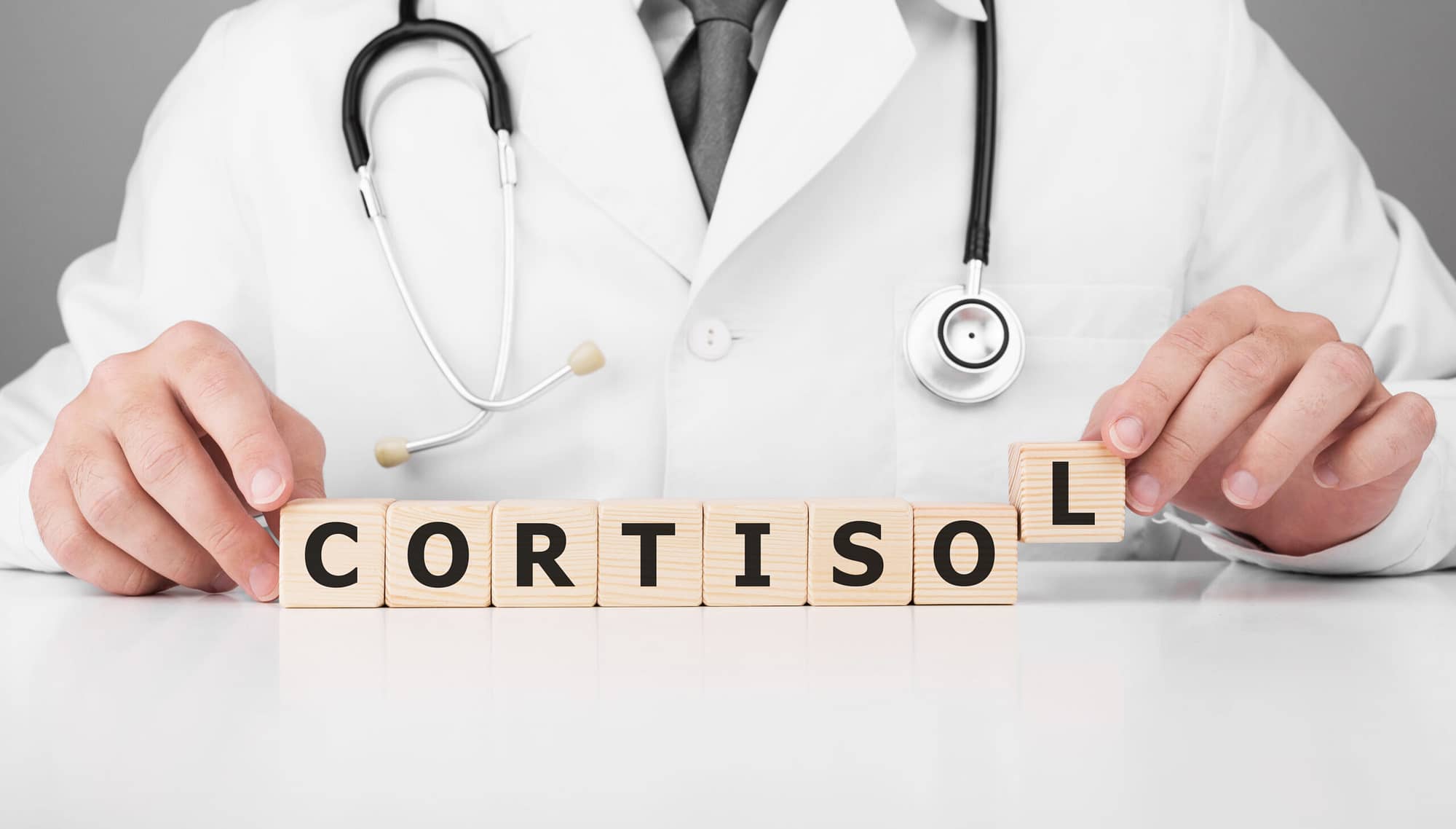Doctor holds wooden cubes in his hands with text CORTISOL