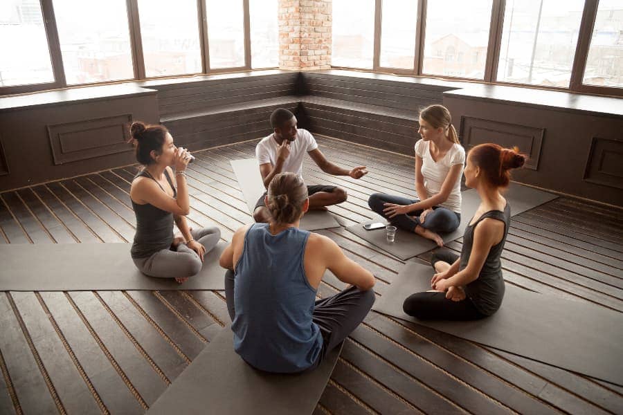 International students speak to each other in yoga studio after class
