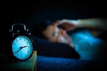Alarm Clock Near Sleeping Person