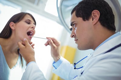 Doctor examines patient's mouth and tonsils