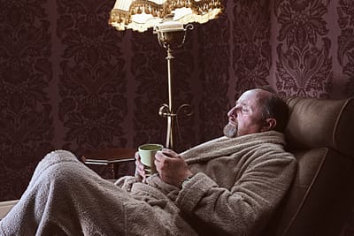 older man in robe with mug in a recliner