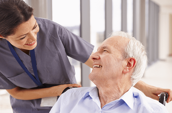 Elderly patient in wheelchair smiling at nurse 