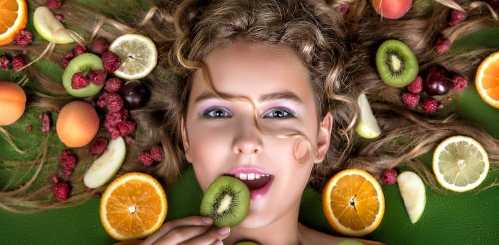 Woman laying on back surrounded by various fruit