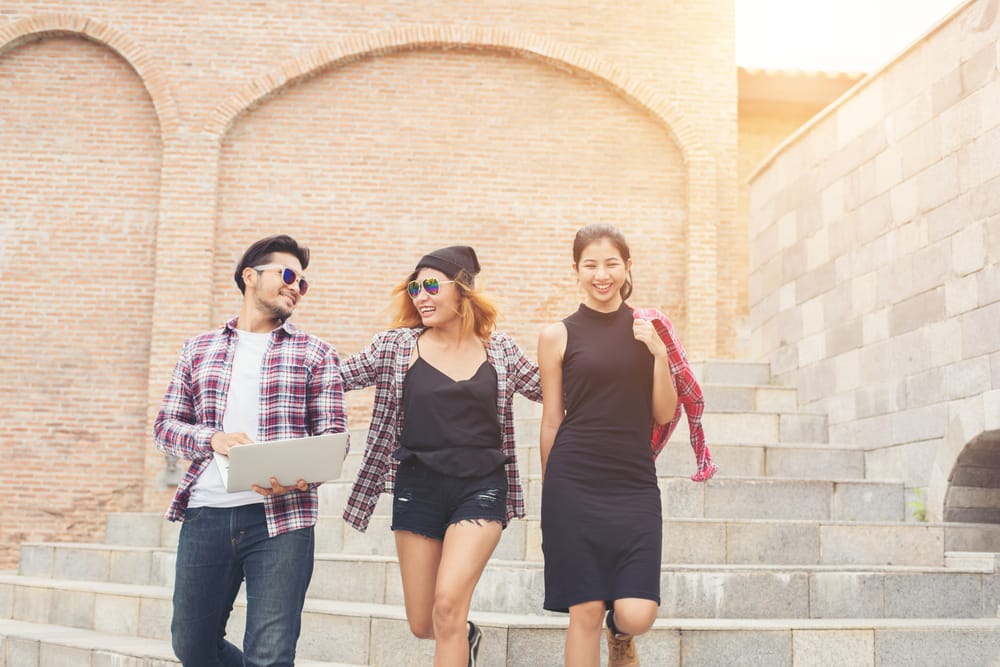 Three college students smiling while walking on campus
