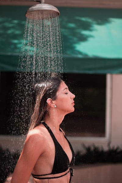 woman rinsing off in a pool side shower