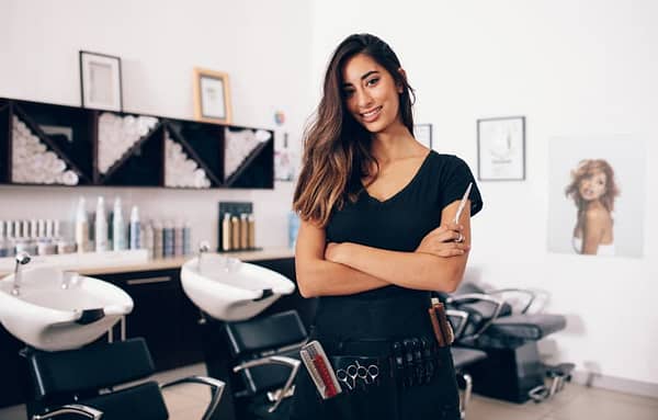 Smiling Hairdressaer In A Salon Holding Scissors In Hand
