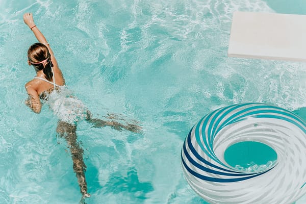 woman swimming in a pool with a diving board and pool float