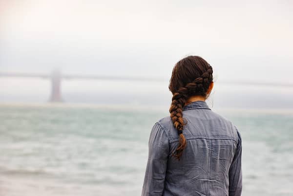 woman with braided hair with her back turned facing the ocean
