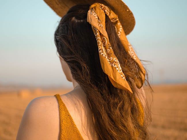 Girl wearing a yellow bandana in her long brown hair.