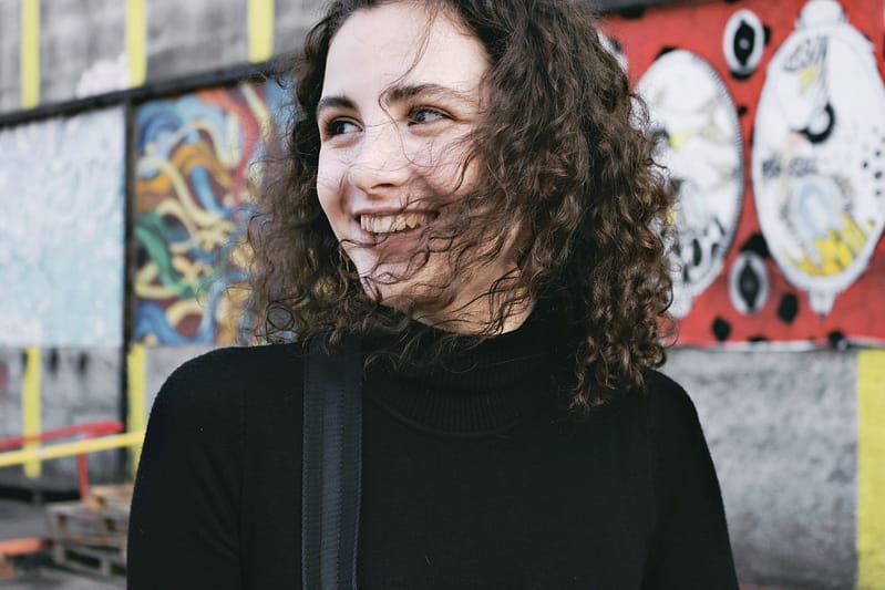 Young woman with permed hair and black shirt smiling