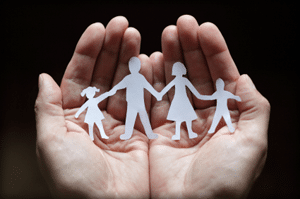 Cupped hands holding paper cutout of family