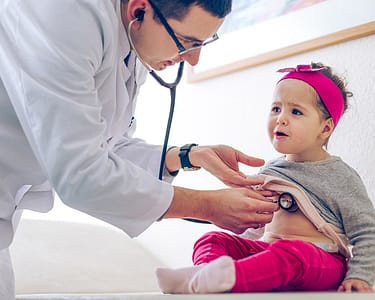 Doctor using a stethoscope to examine a toddler.