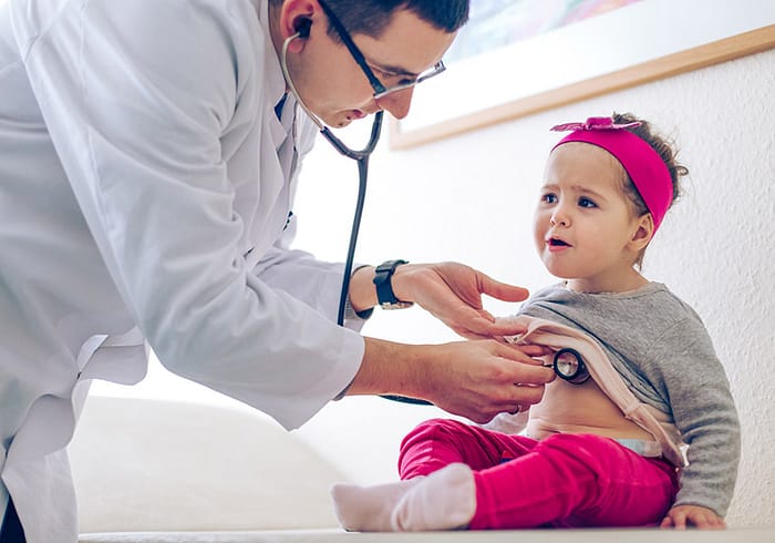 Doctor using a stethoscope to examine a toddler.