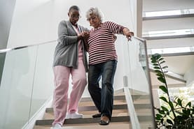 Physical therapist assistant helps patient on stairs