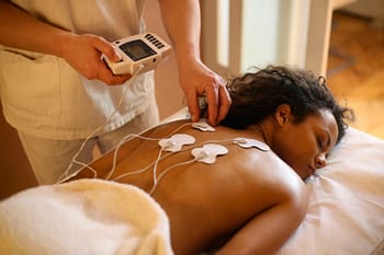 Therapist applies electrodes to a client for electrostimulation treatment