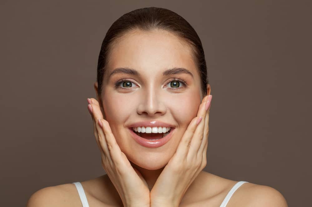 Woman looking at camera while touching their face and smiling