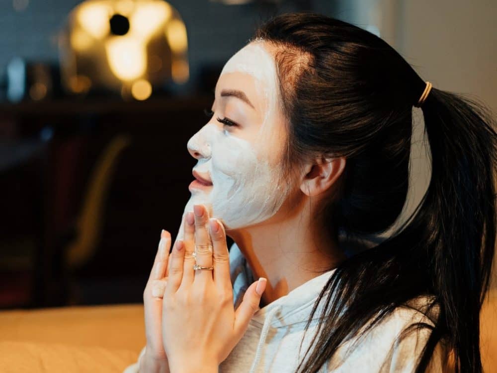 Woman applying a face mask at home.