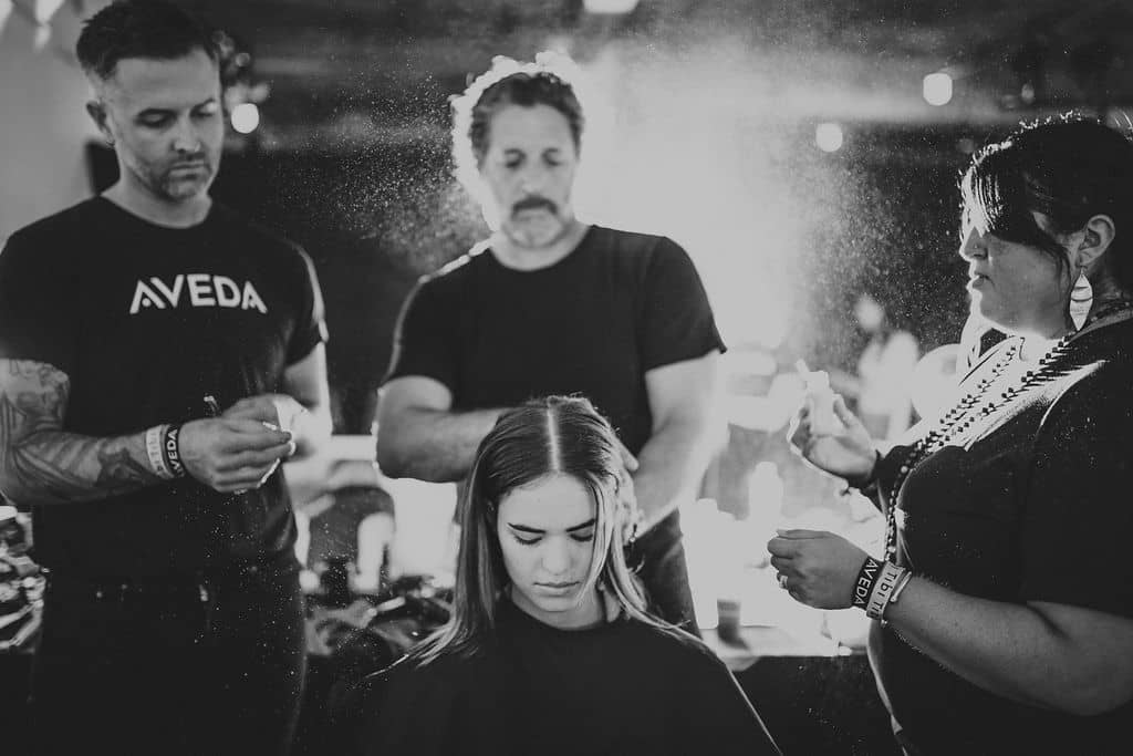Two students observing Aveda instructor giving haircut to client