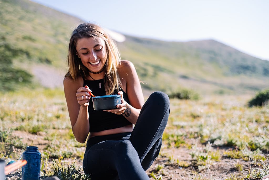 girl eating out of a bowl in wilderness