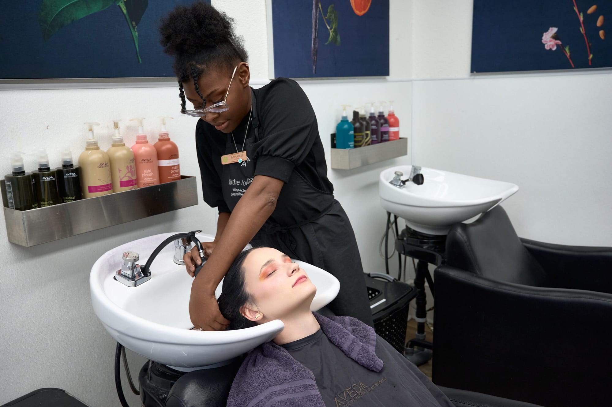 Hairstylist washing client’s hair in wash sink in hair salon