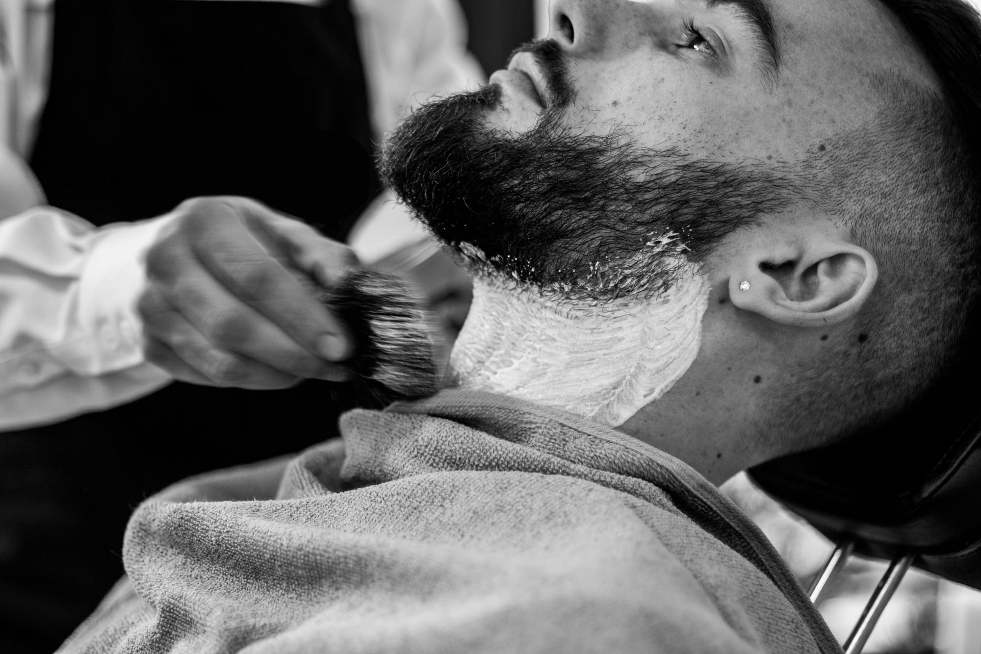 A barber prepares a man for a shave