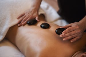 Closeup of massage therapist arranging hot stones on client's back