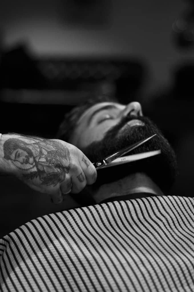 man getting his beard trimmed with scissors