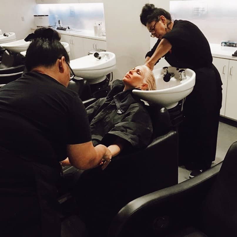 Two barber school students make client comfortable in chair while washing hair