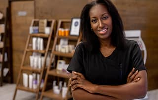 Smiling esthetician with shelves of salon products in background