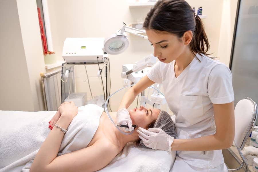 Female esthetician performing professional skin treatment to a female client