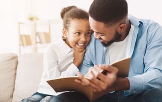 Father Studying On Couch With Daughter