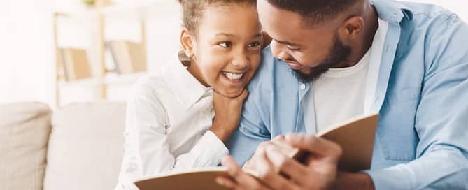 Father Studying On Couch With Daughter