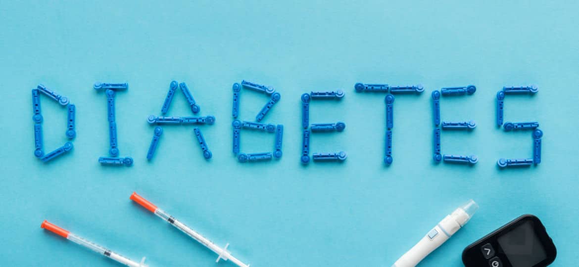 diabetes word with syringes and medical equipment on blue background