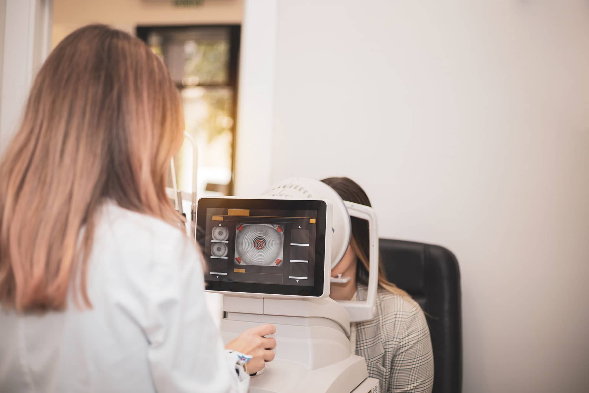 an optometrist uses a wide cone corneal topographer to take info
