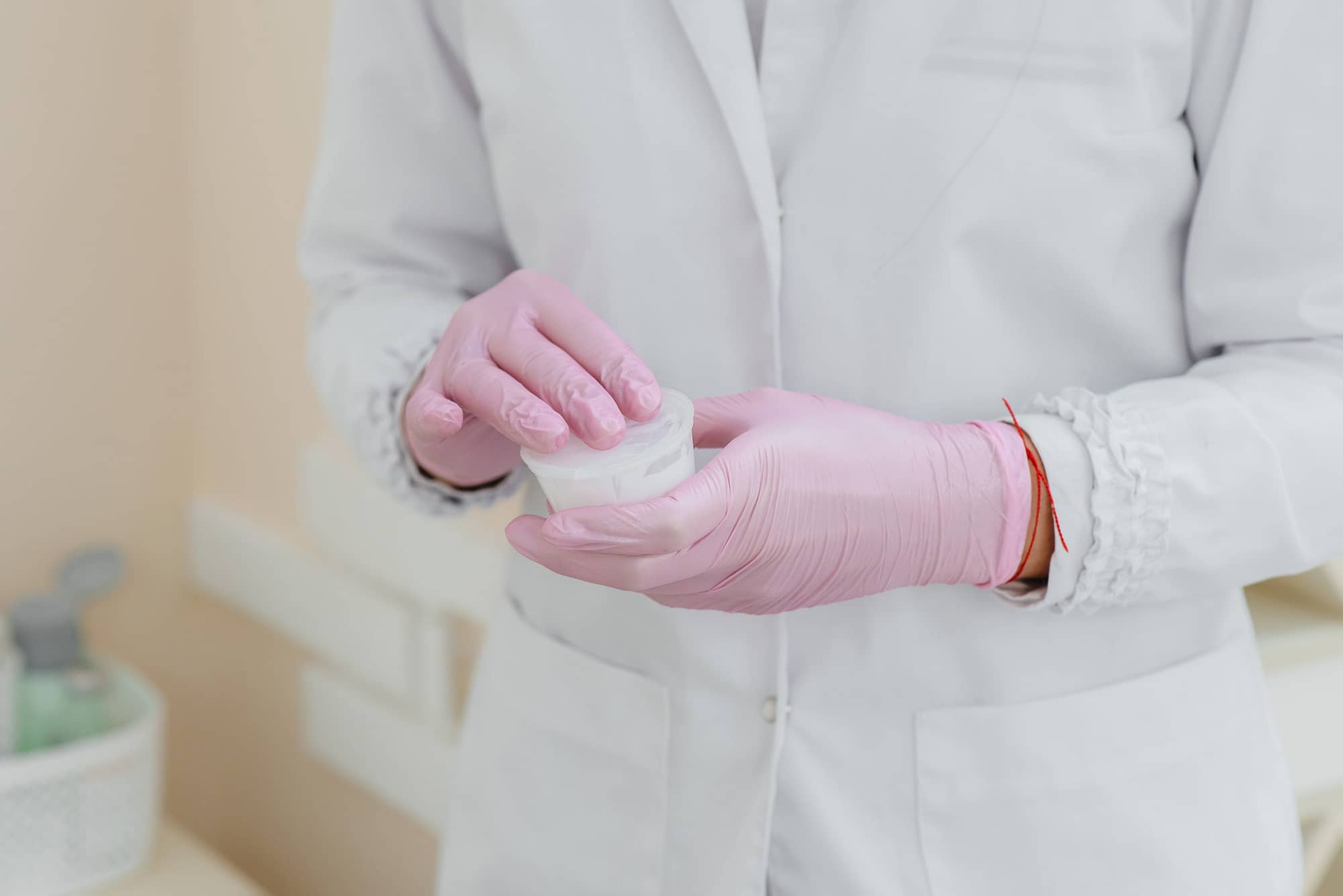 A cosmetologist holds a large – scale anesthesia ointment in his hands.