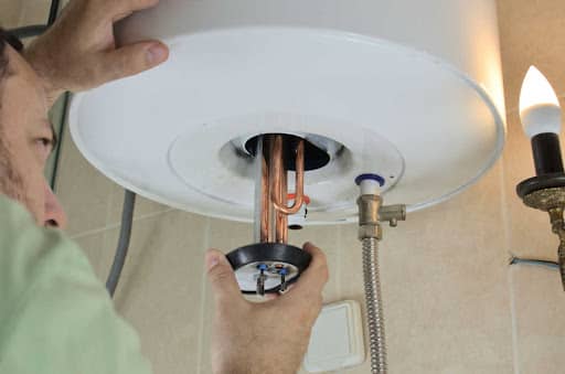 An HVAC technician performs work on a hot water heater.