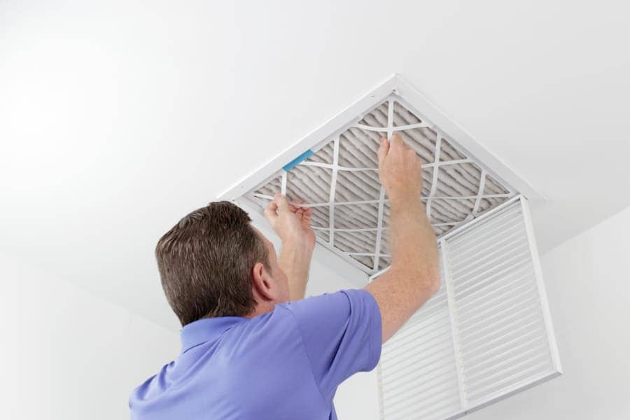Man installing home air filter in ceiling vent