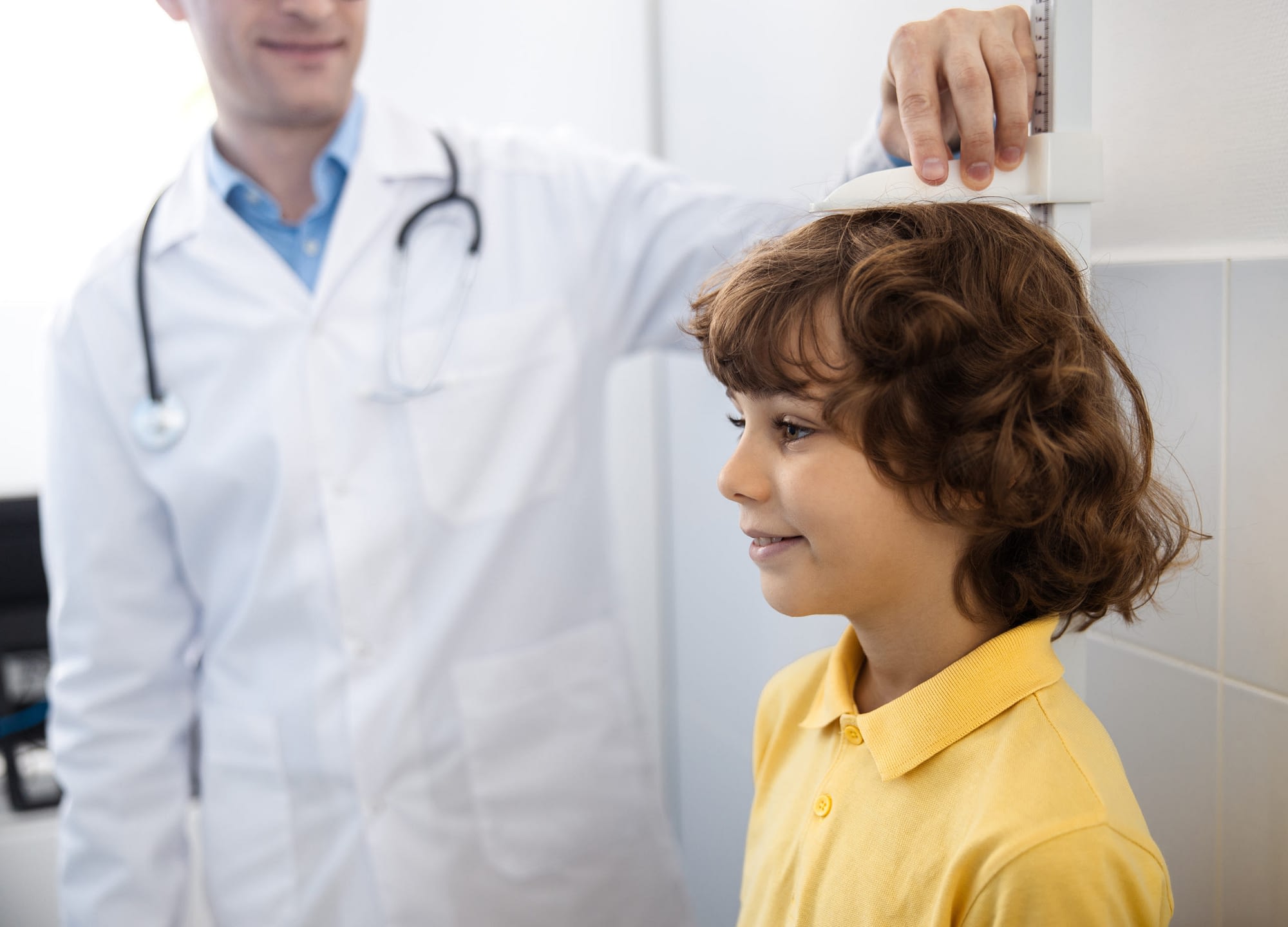 Curly boy is being measured by doctor stock photo