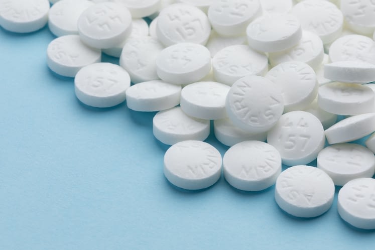 White aspirin pills on blue paper background, soft focus