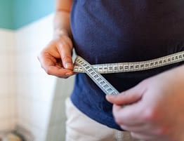 Man Measuring Waist To Monitor Weight Loss